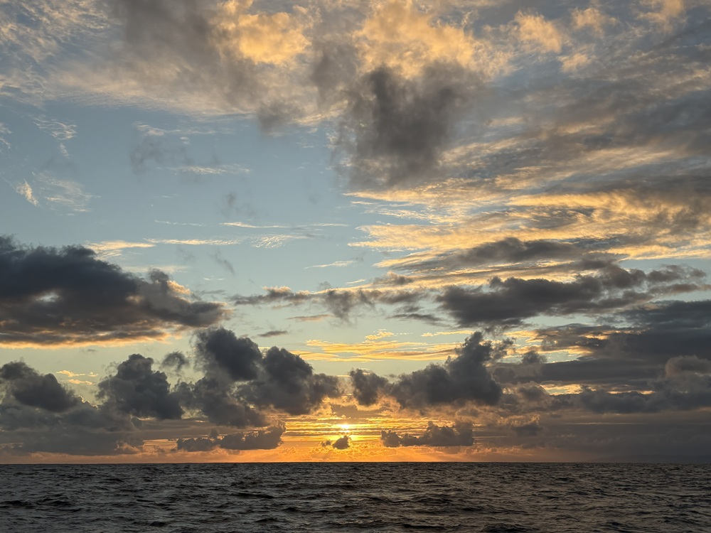Craig Spiesman photo featuring dark clouds and warm light above open ocean water