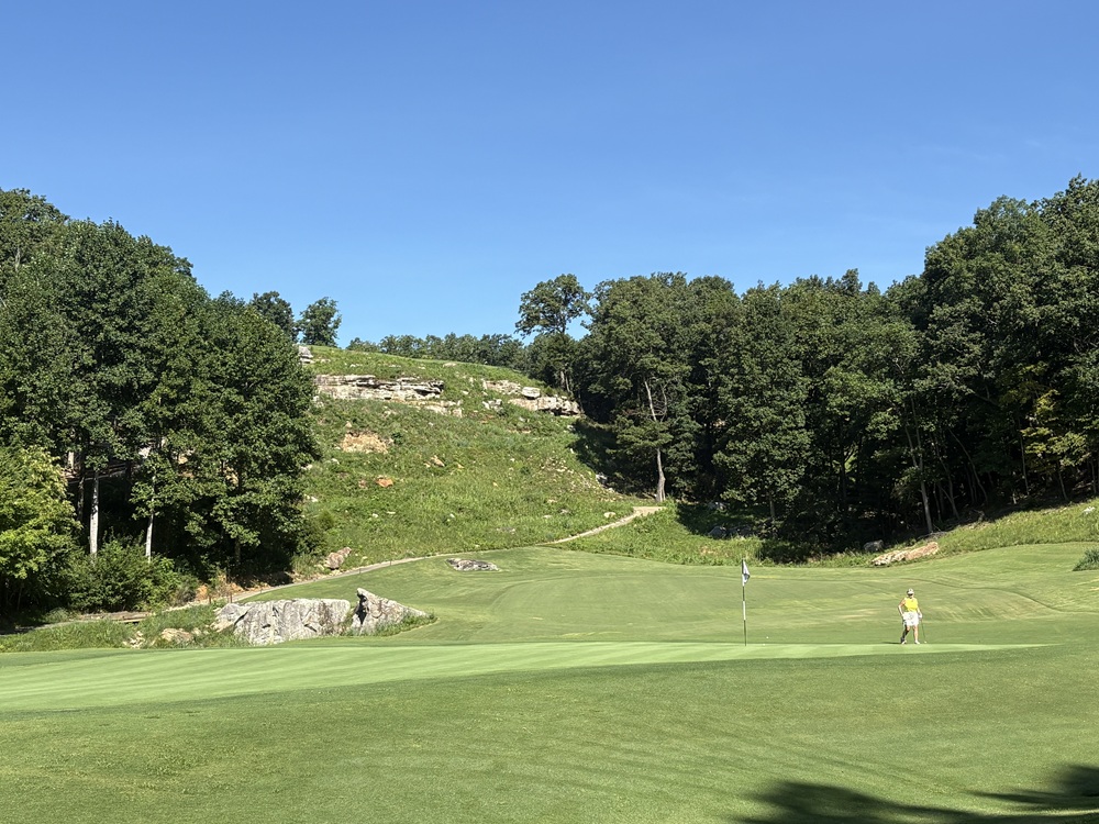 Craig Spiesman photo featuring a golfer near the green with wooded hills behind