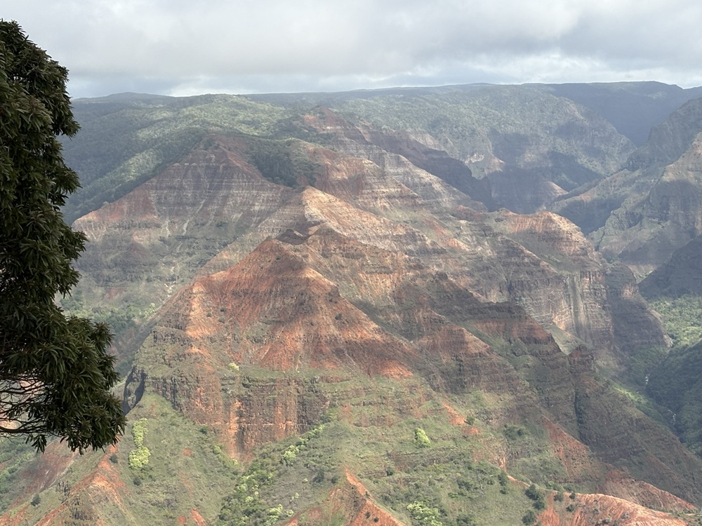 Craig Spiesman photo showing layered mountain walls with red rock and green slopes